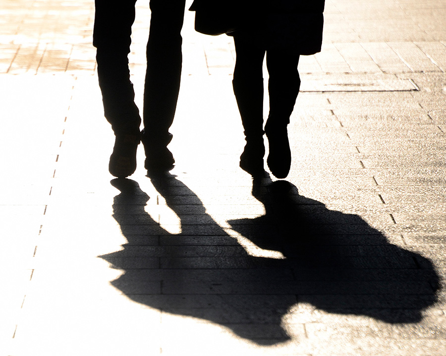 Couple walking shadows showing on sidewalk. Deciding whether or not to continue the relationshpi